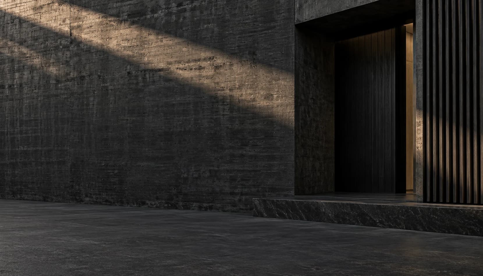 Raking light across black concrete and a recessed architectural exterior